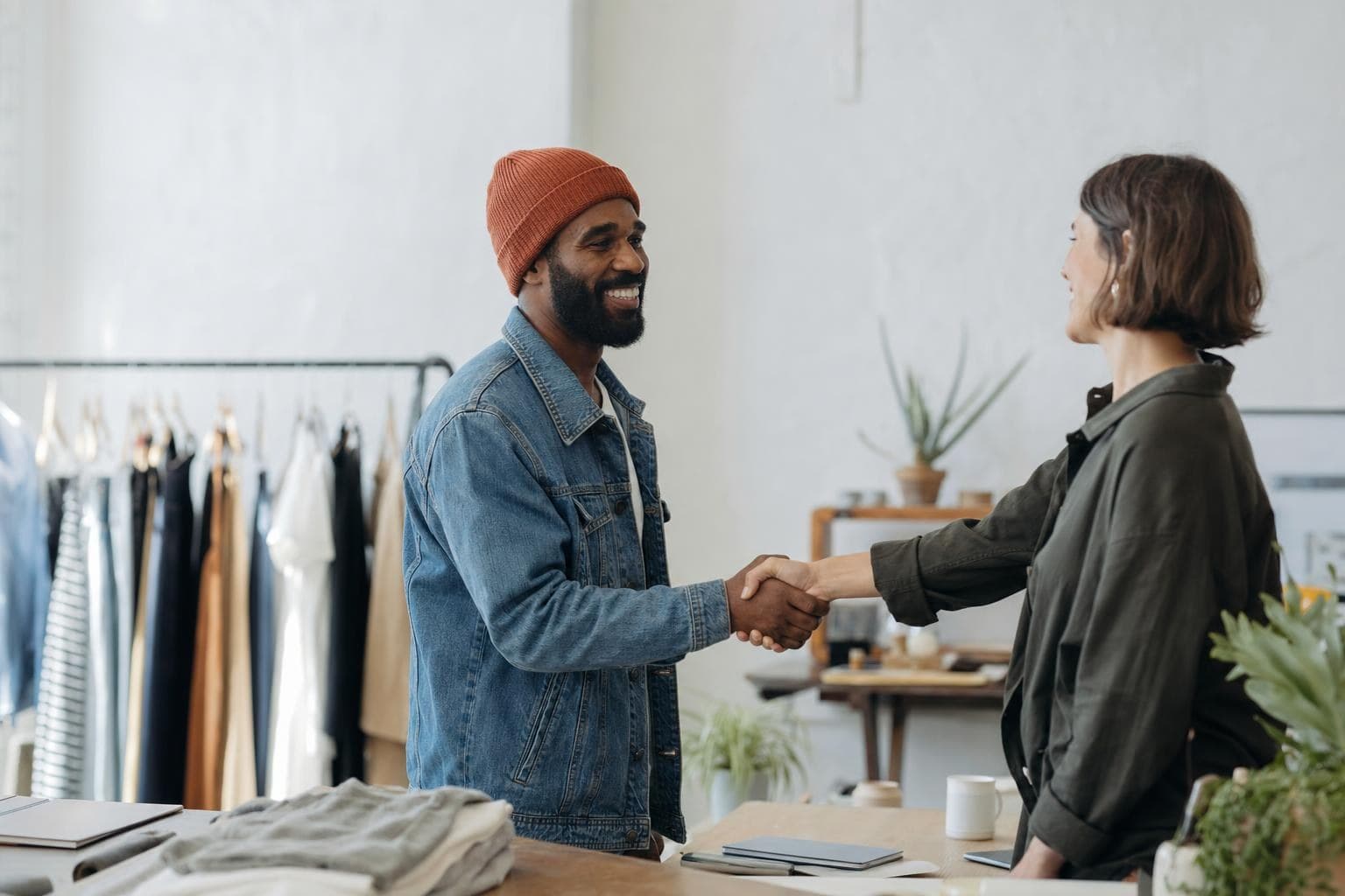 Two small-business owners shaking hands on a collaboration in a bright space.