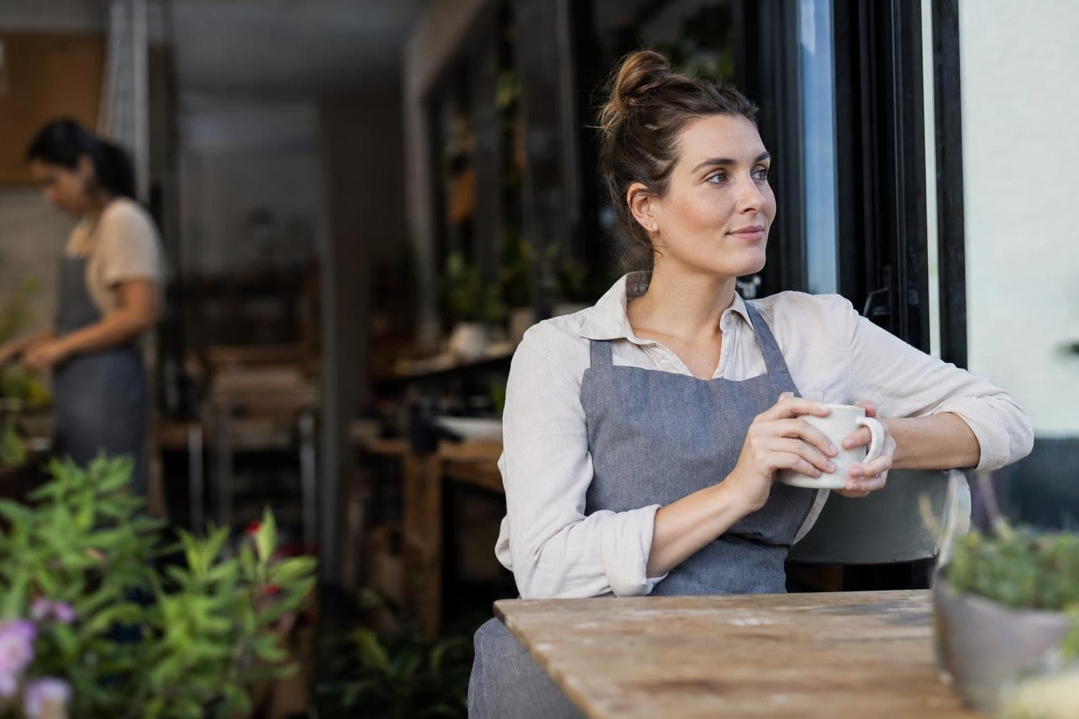 A photo of a tired business owner taking a genuine restful break with a coffee in calmer light.