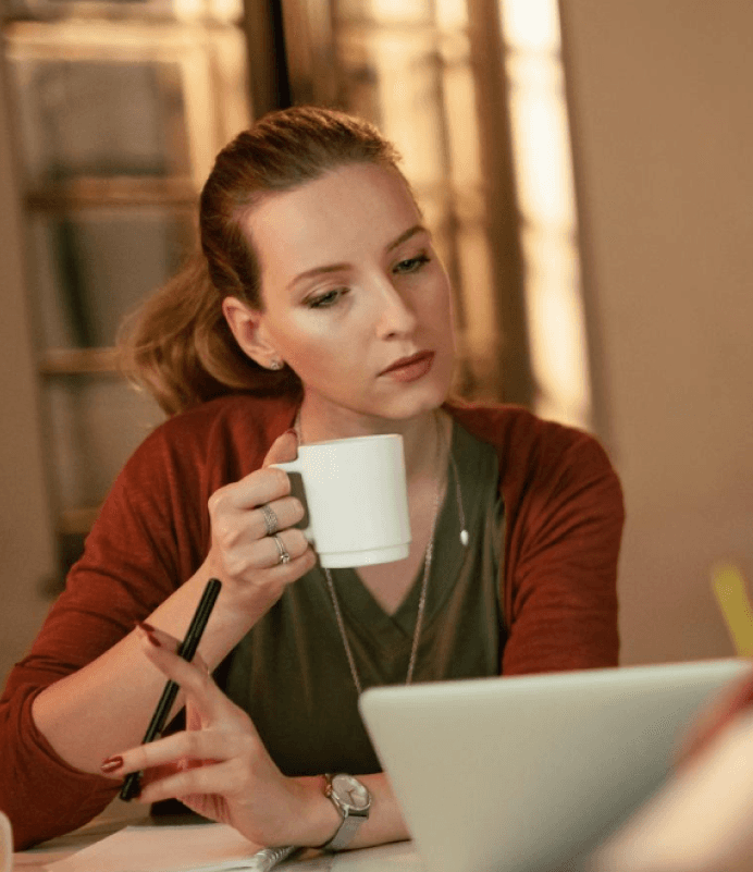 Founder taking a coffee break while reviewing work on a laptop