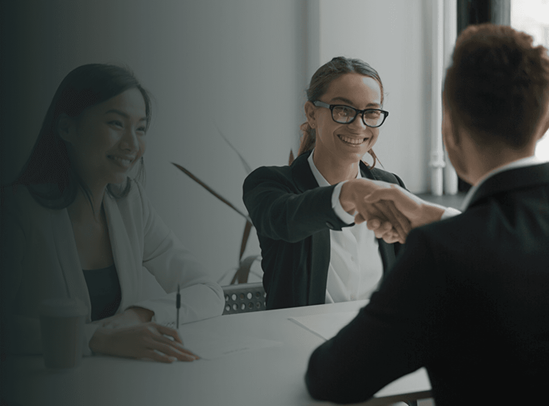Two professionals shaking hands across a desk